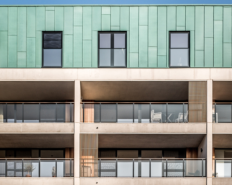 Neubau mit grüner Metallfassade und Balkonen